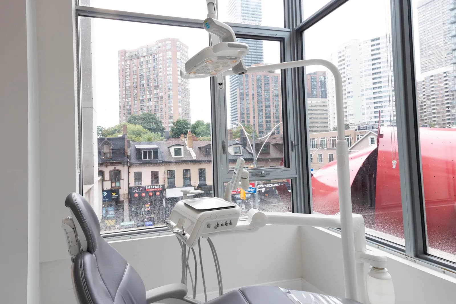 Corner dental treatment room with floor-to-ceiling windows overlooking Yonge Street, Toronto
