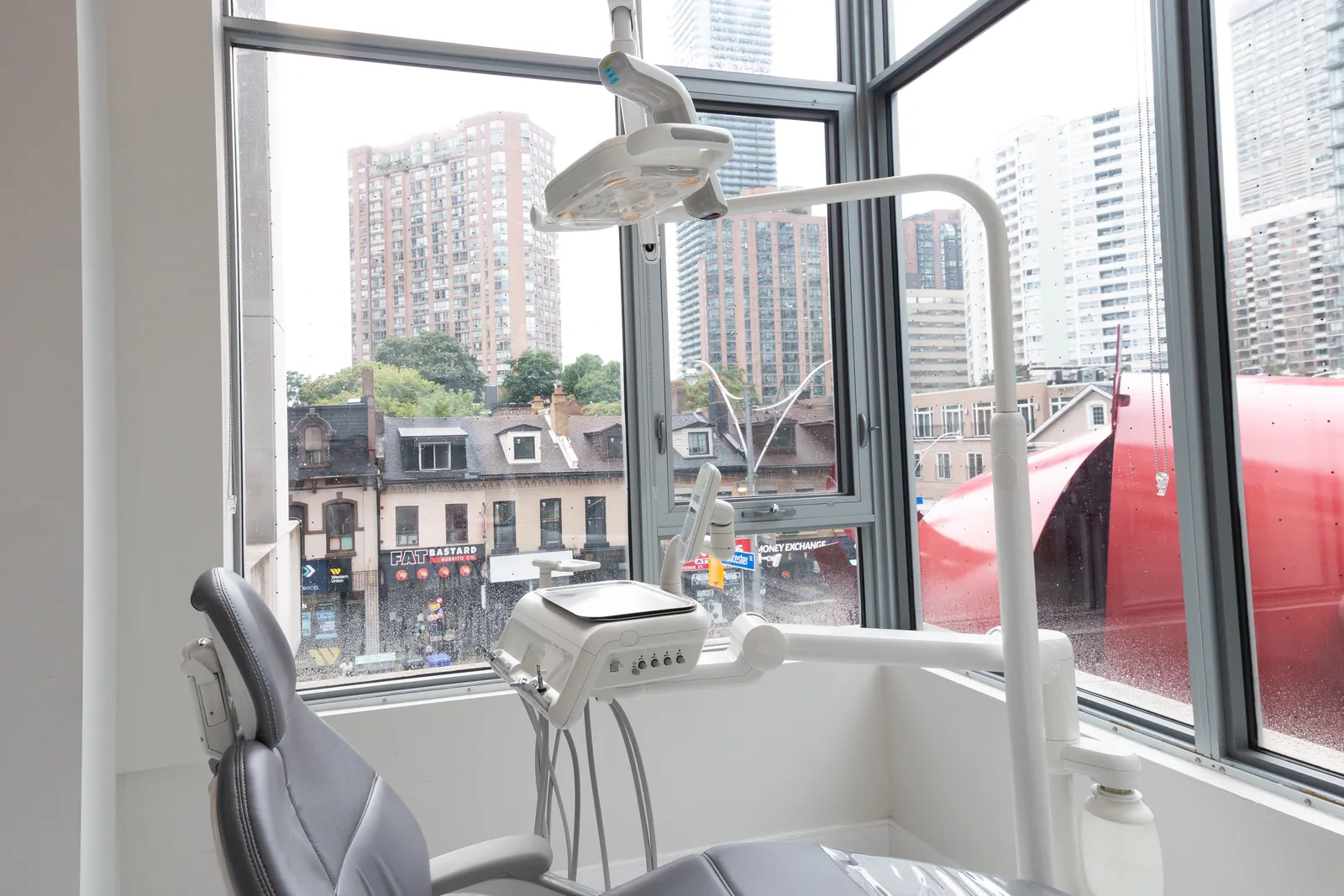 Corner dental treatment room with floor-to-ceiling windows overlooking Yonge Street in downtown Toronto